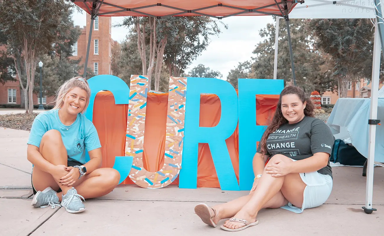 Students sitting next to "Cure" sign