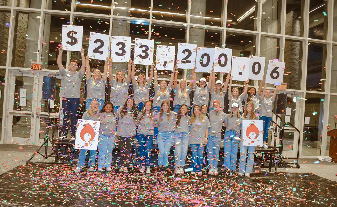 UA Miracle students holding signs for $233,200.06 with confetti everywhere