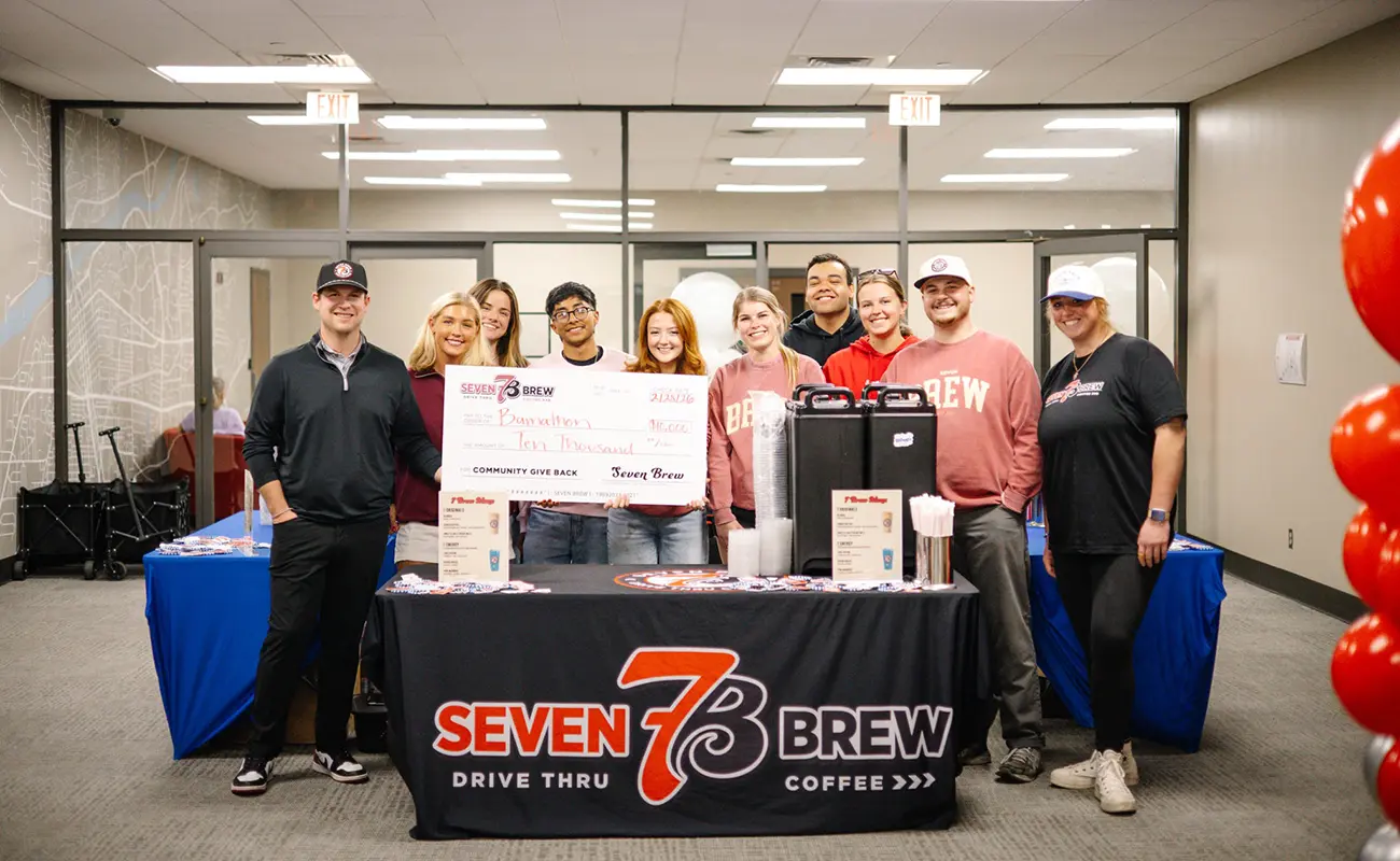 Seven Brew Coffee staff a table and hold a check to support Bamathon